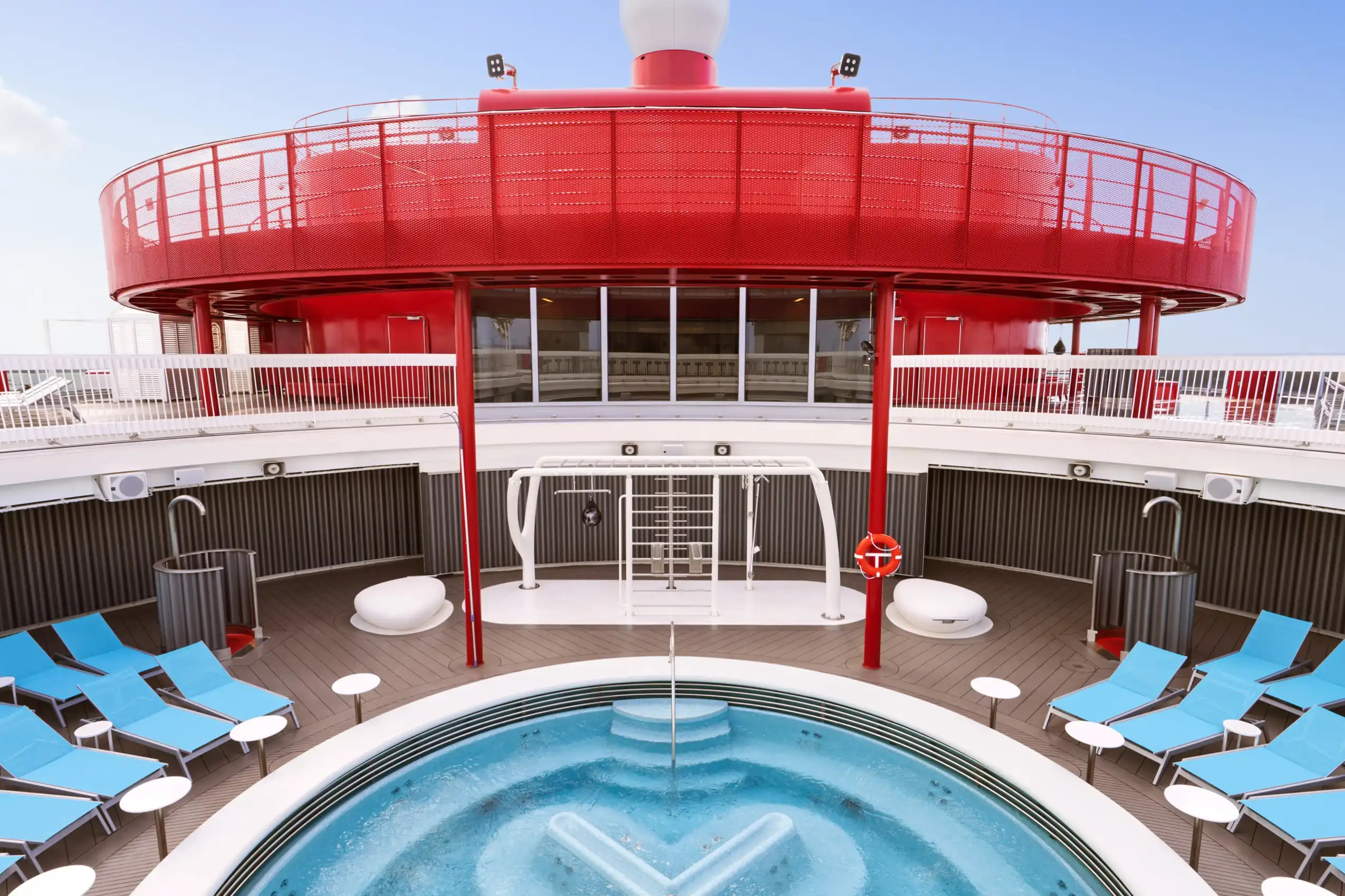 Outdoor pool surrounded by blue lounge chairs on cruise ship deck